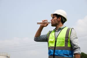osha heat safety program - man hydrating on job site on a hot day