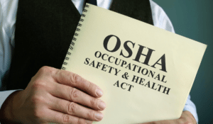 A person holding a booklet which reads "OSHA Occupational Health and Safety Act"