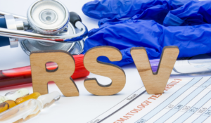 A stethoscope, medical chart, and rubber medical gloves, arranged around large wooden block letters that spell out RSV